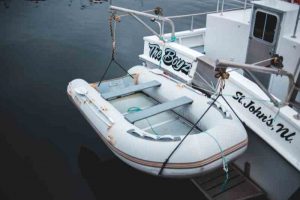 Pequeno bote branco, suspenso pelo barco em lago.